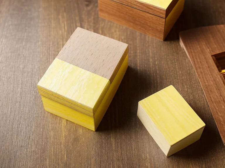 Ein gelber Karteikasten aus Holz mit handgeschriebenen Notizen zur Ahnenarbeit auf einem Schreibtisch.