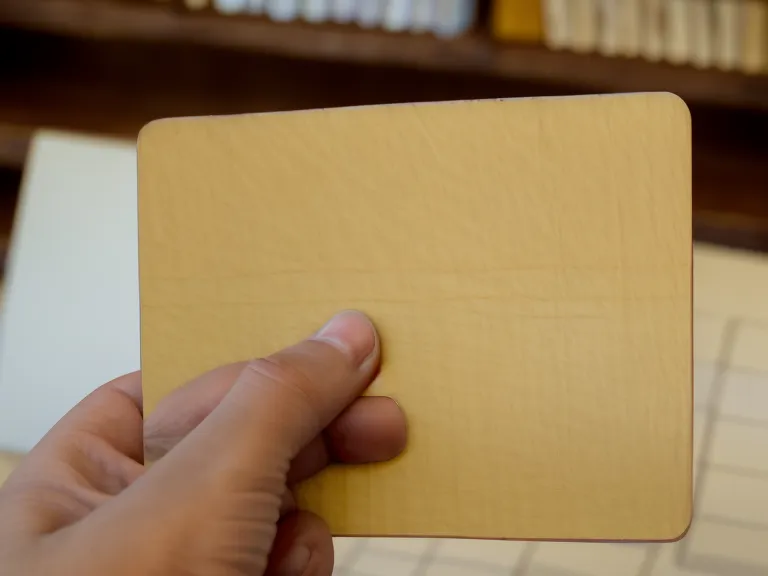 Nahaufnahme einer Hand, die eine Karteikarte in einen gelben Karteikasten sortiert.
